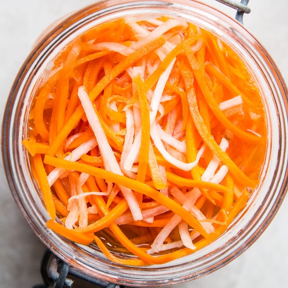 a glass jar of quick pickled carrots and radishes