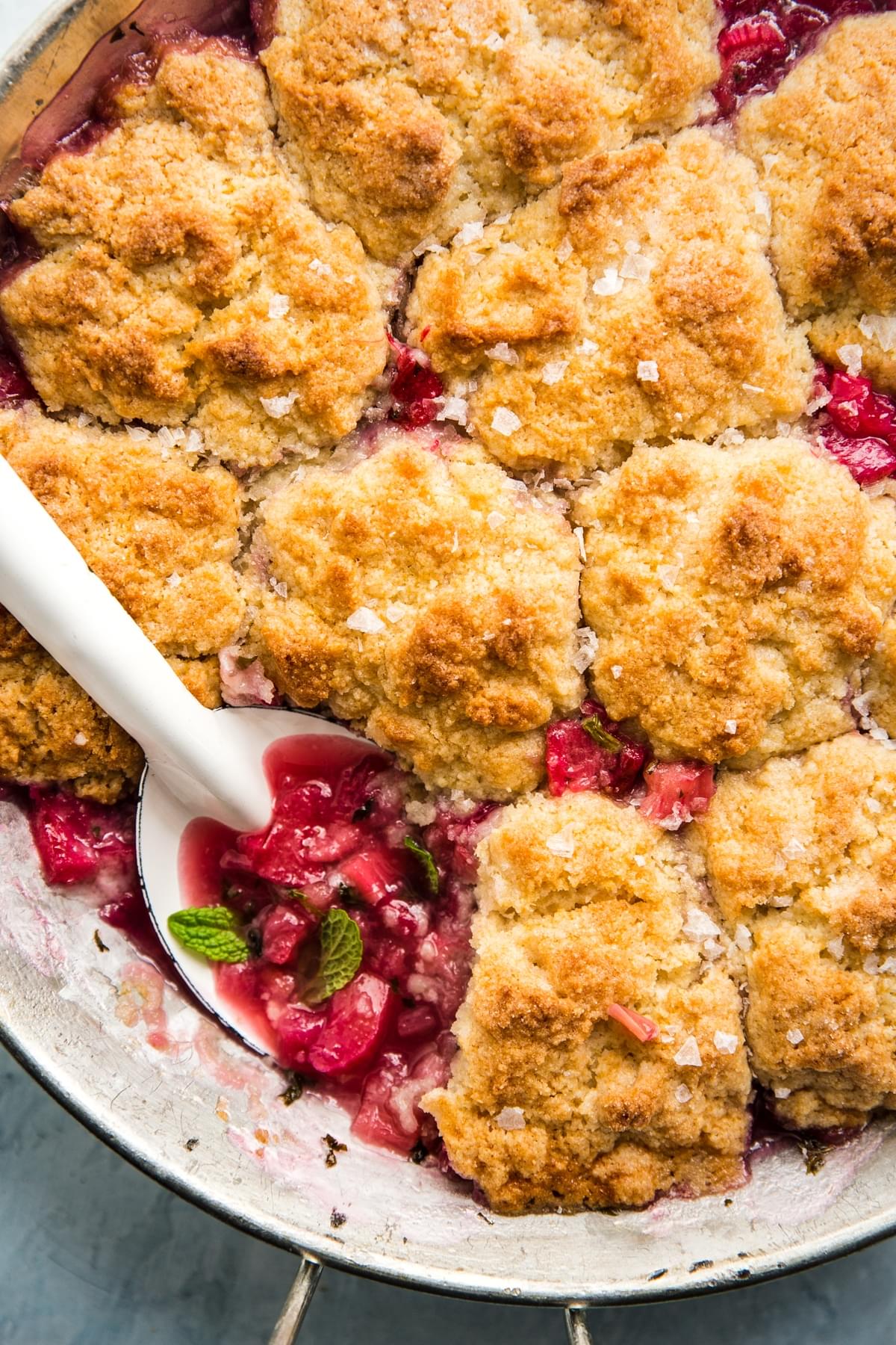 spoon scooping out rhubarb cobbler  with mint
