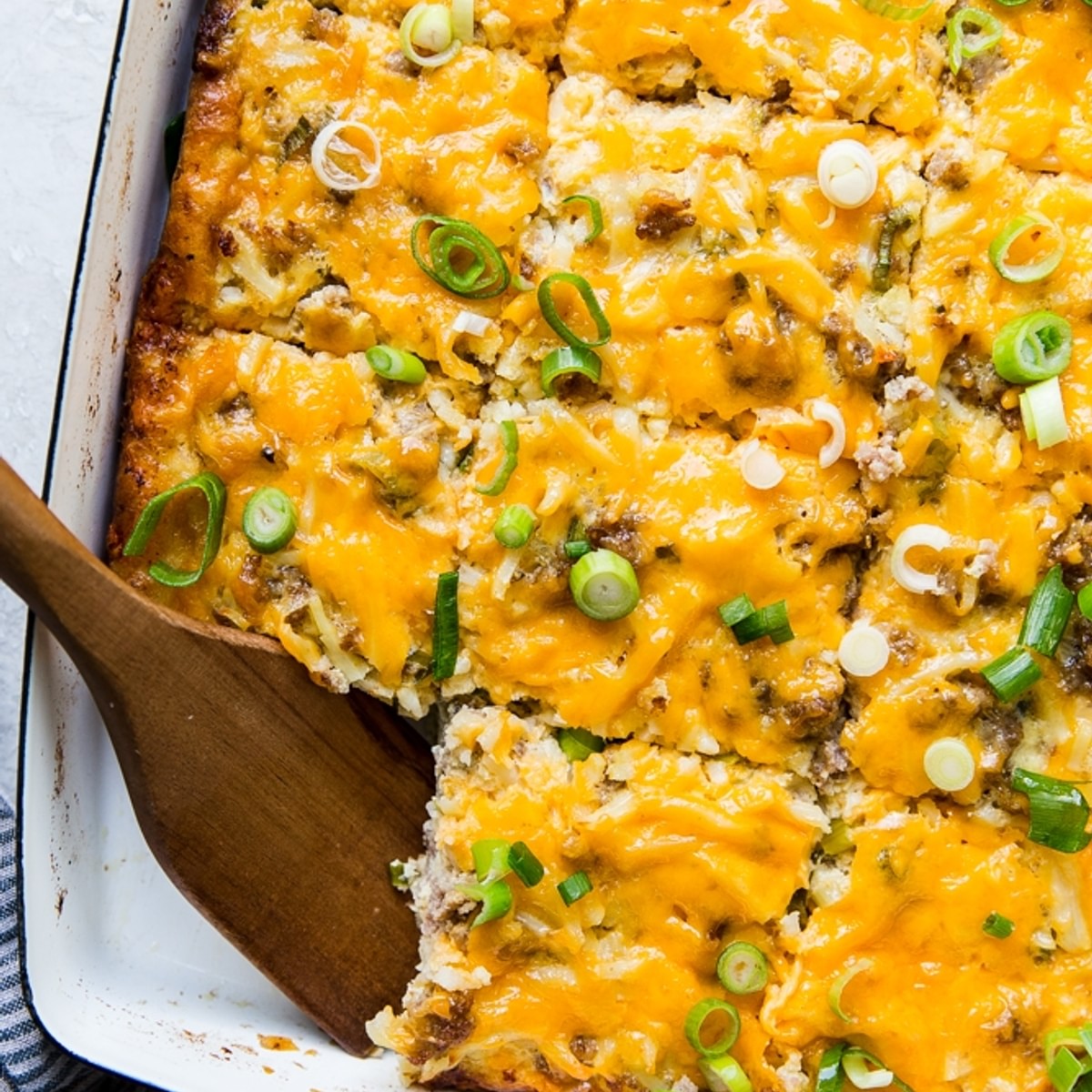 Sausage Breakfast Casserole with hash browns and green onions in a baking dish
