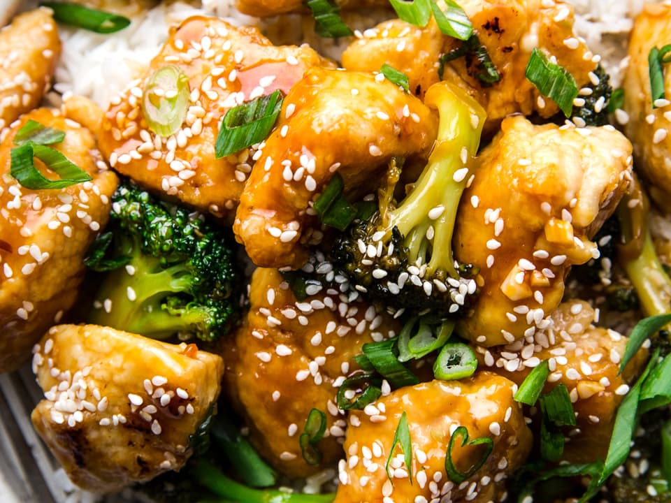 sesame chicken with broccoli and rice on a plate with a fork