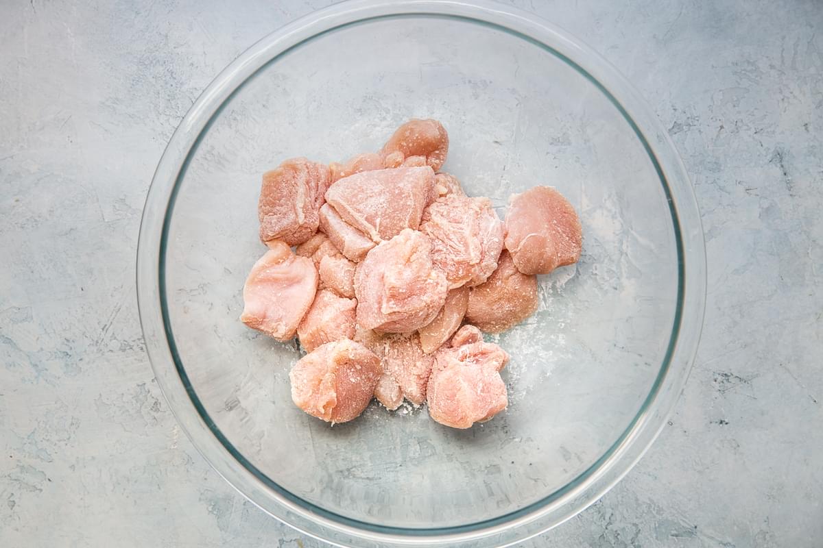 raw chicken pieces with salt and cornstarch in a bowl