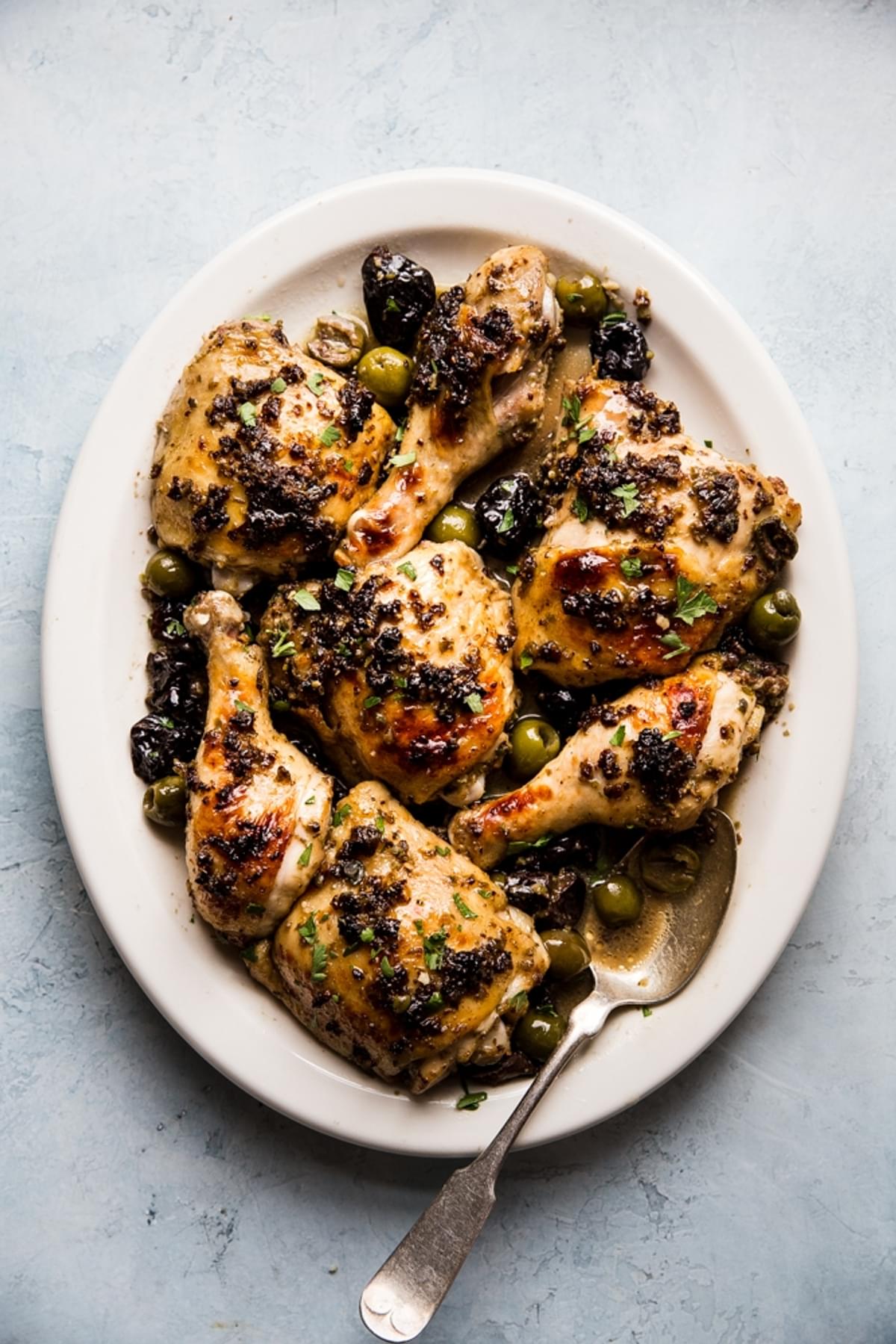 chicken marbella on a plater with olives, capers, dates and a butter pan sauce