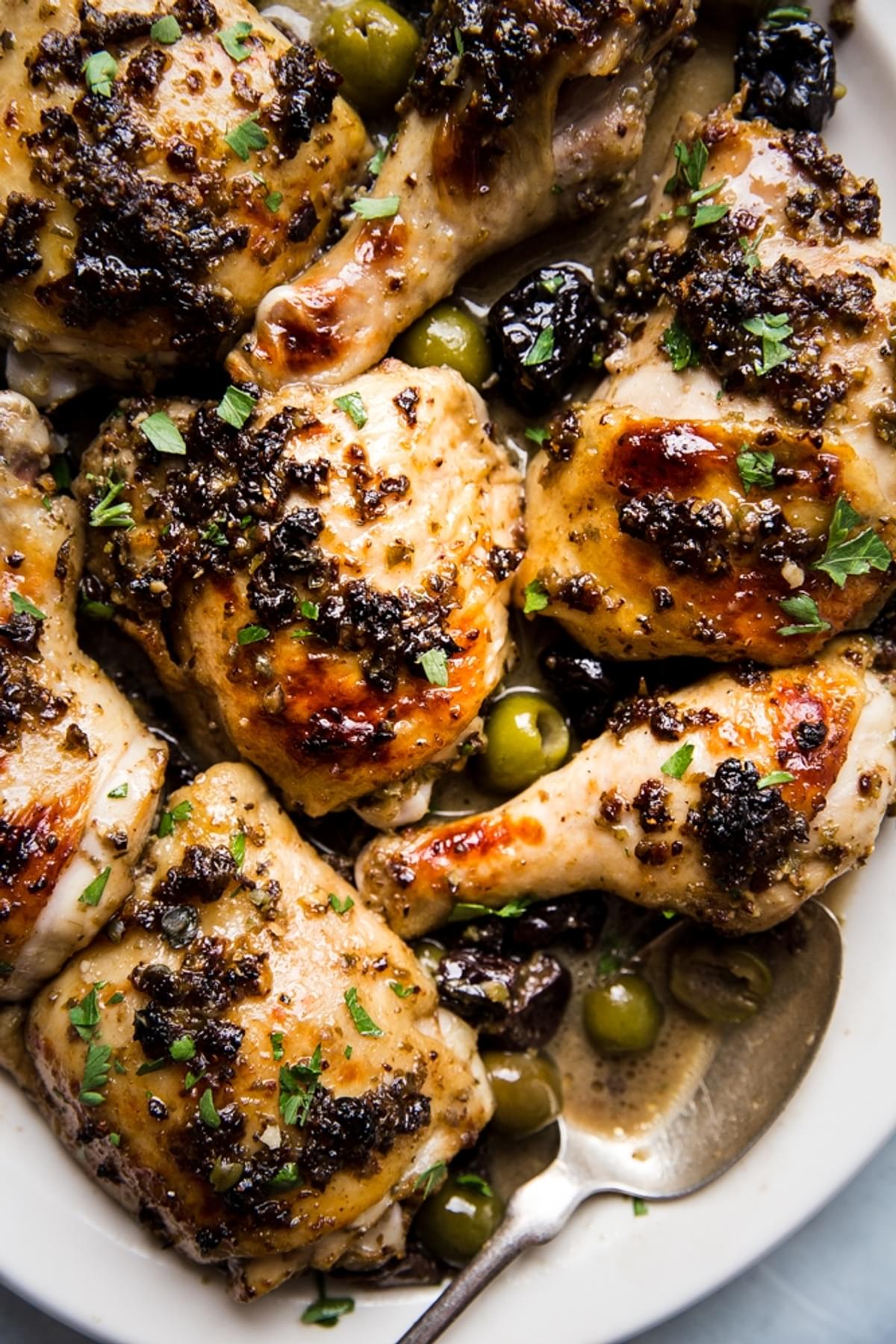 chicken marbella on a plater with olives, capers, dates and a butter pan sauce