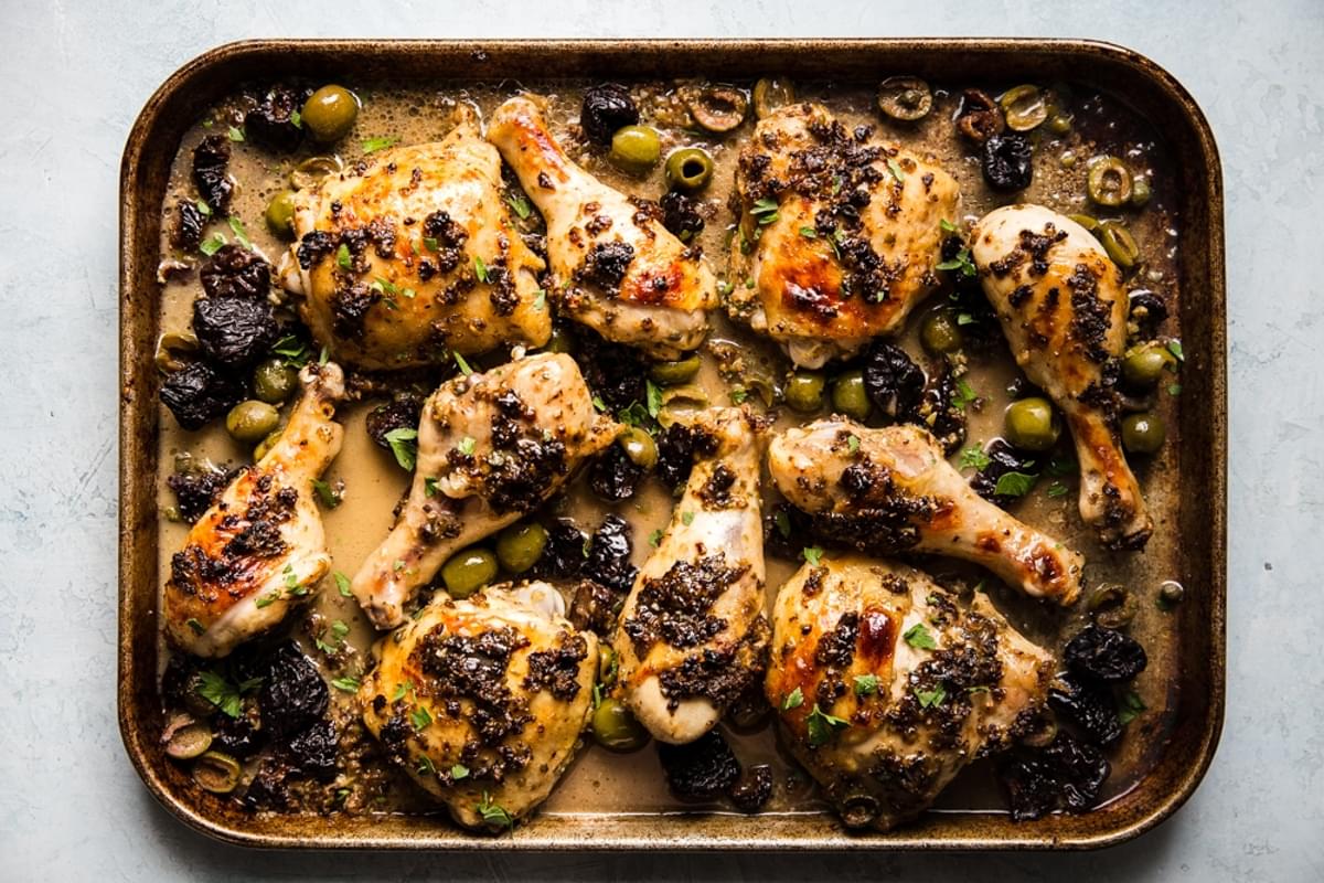 sheep pan chicken marbella on a sheet pan with olives, capers, garlic, prunes, and a white wine sauce