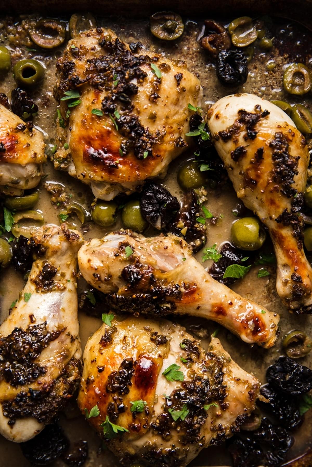 homemade chicken marbella with olives, prunes, capers and a pan sauce on a sheet pan