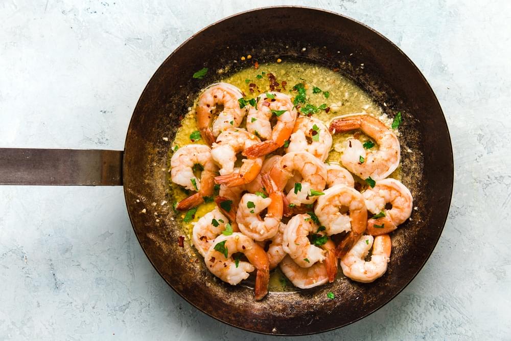 shrimp scampi in garlic butter in a skillet topped with parsley
