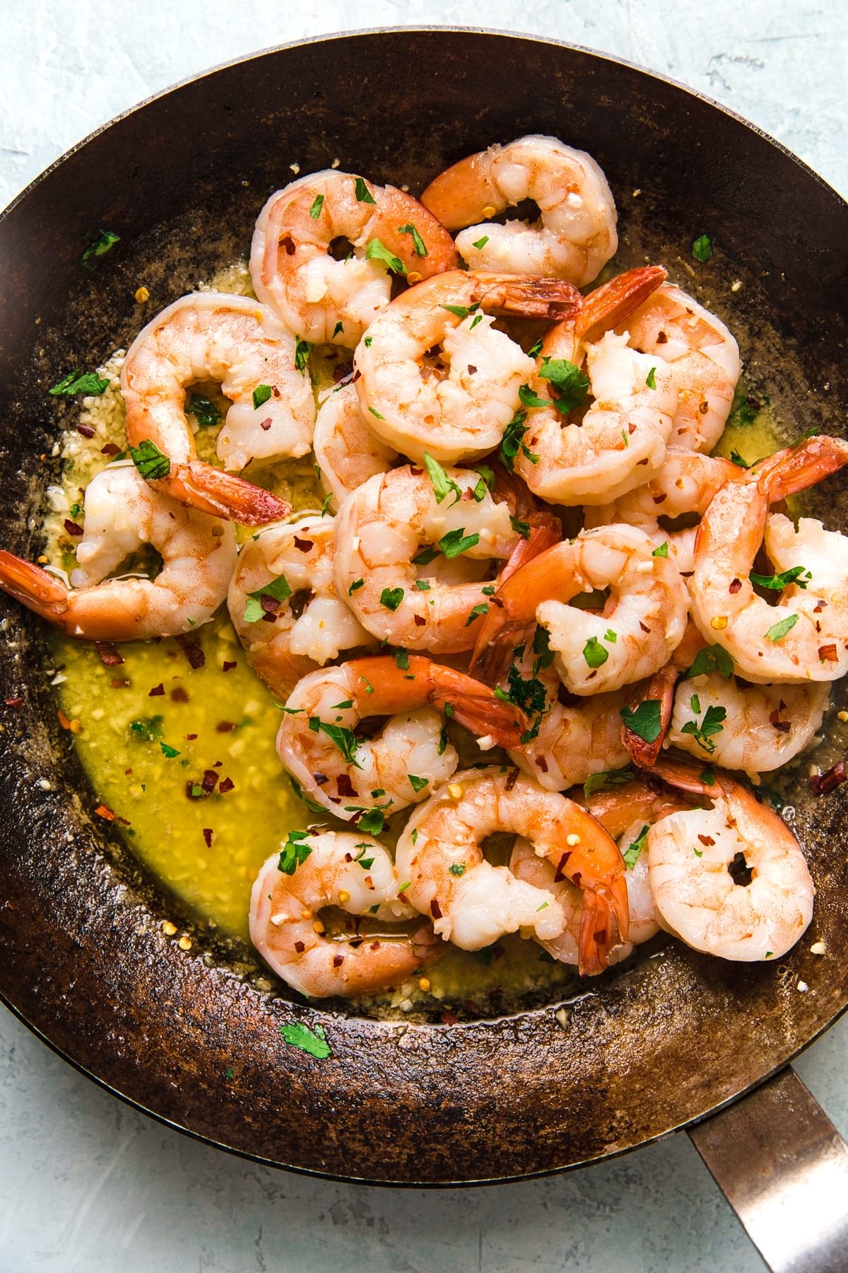 Homemade shrimp scampi in a large metal skillet topped with fresh parsley
