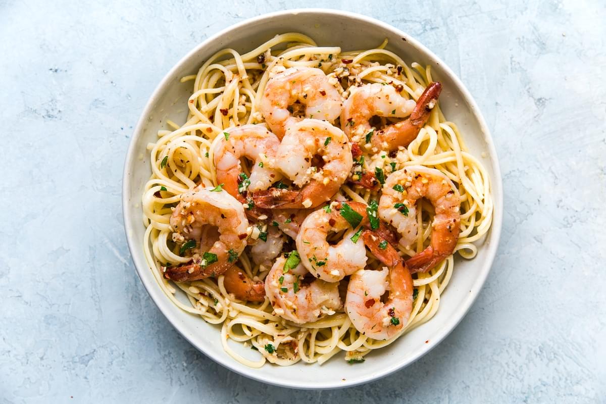 shrimp scampi over pasta in a white bowl