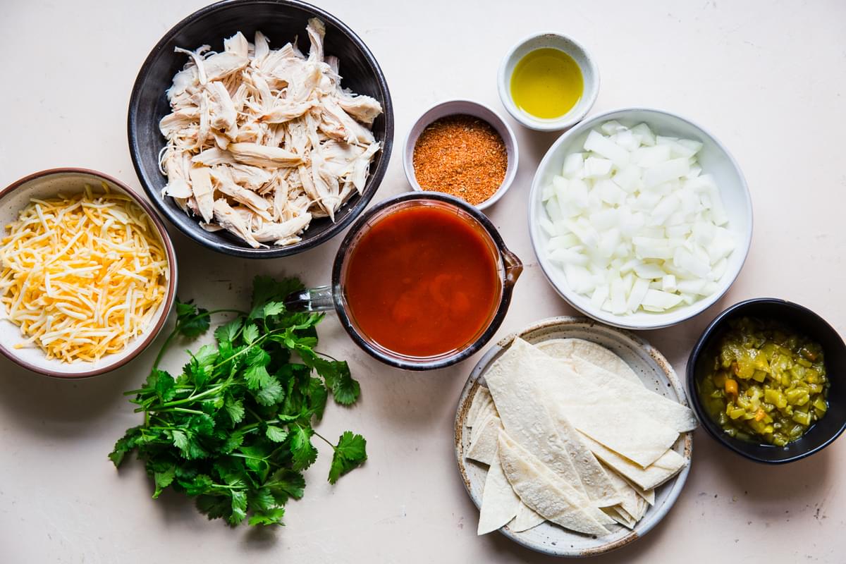 Ingredients for chicken enchilada skillet including rotisserie chicken, shredded cheese, tortillas and  enchilada sauce