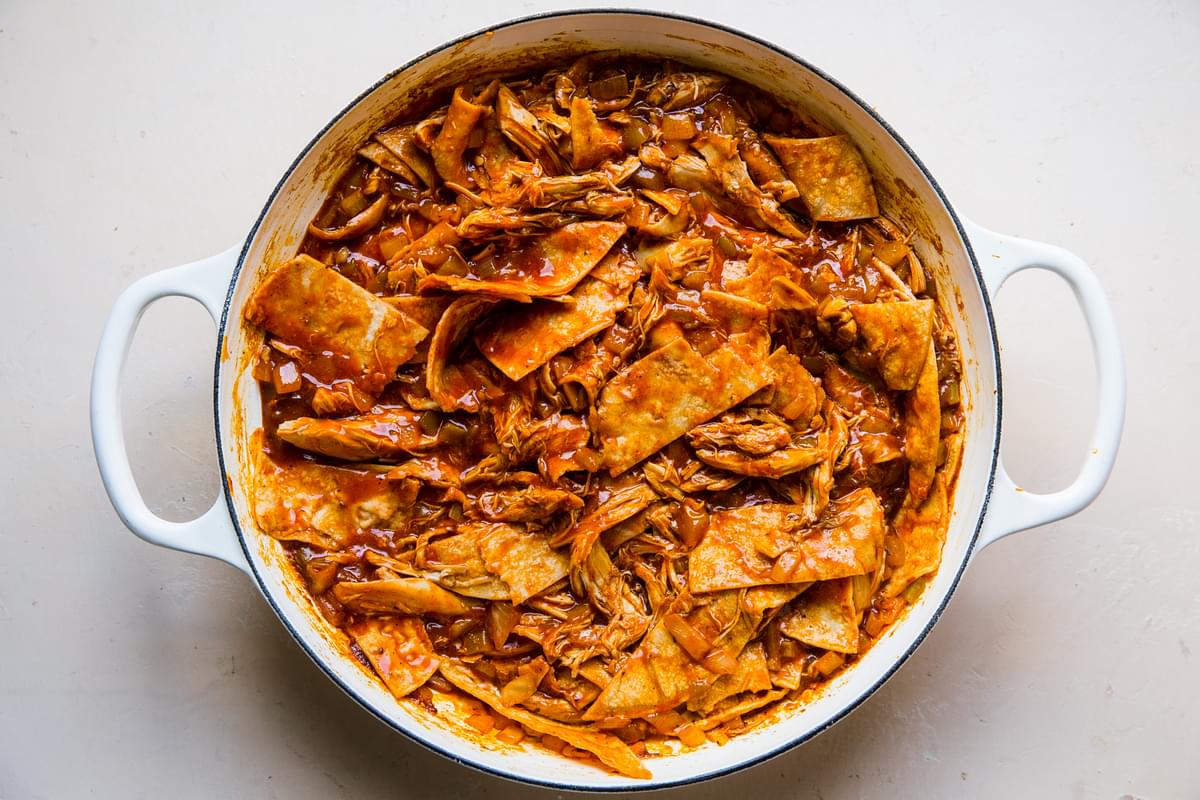 shredded chicken mixed with large corn tortilla strips and red enchilada sauce