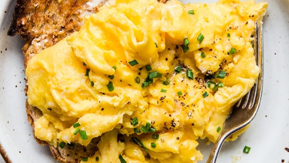 Soft Scrambled Eggs on a plate with chives and toasted bread