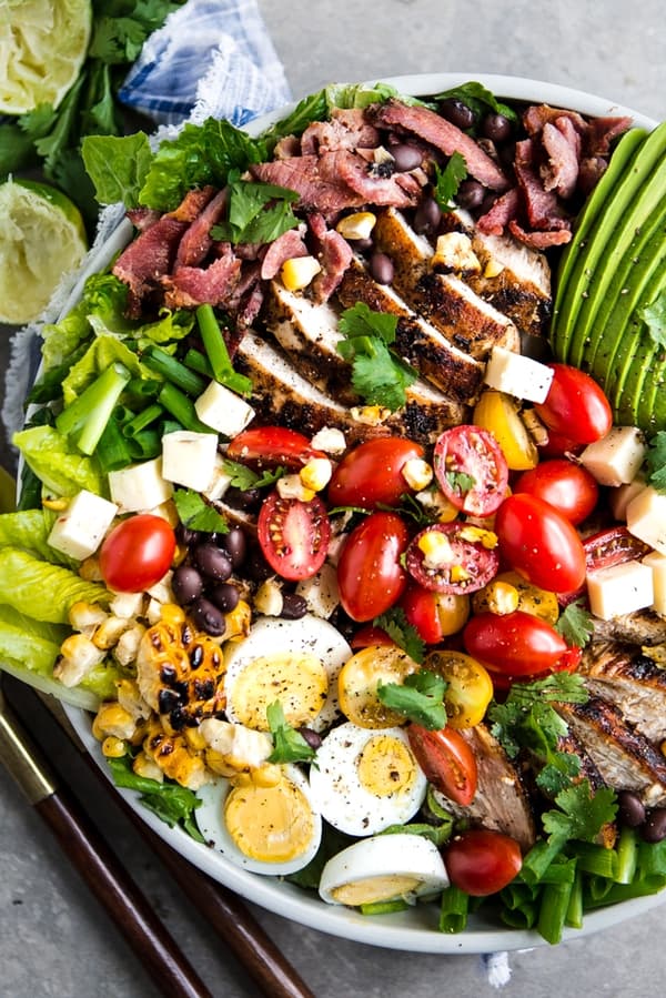 southwest cobb salad with bacon, chipotle dressing, avocado, corn and beans in a bowl