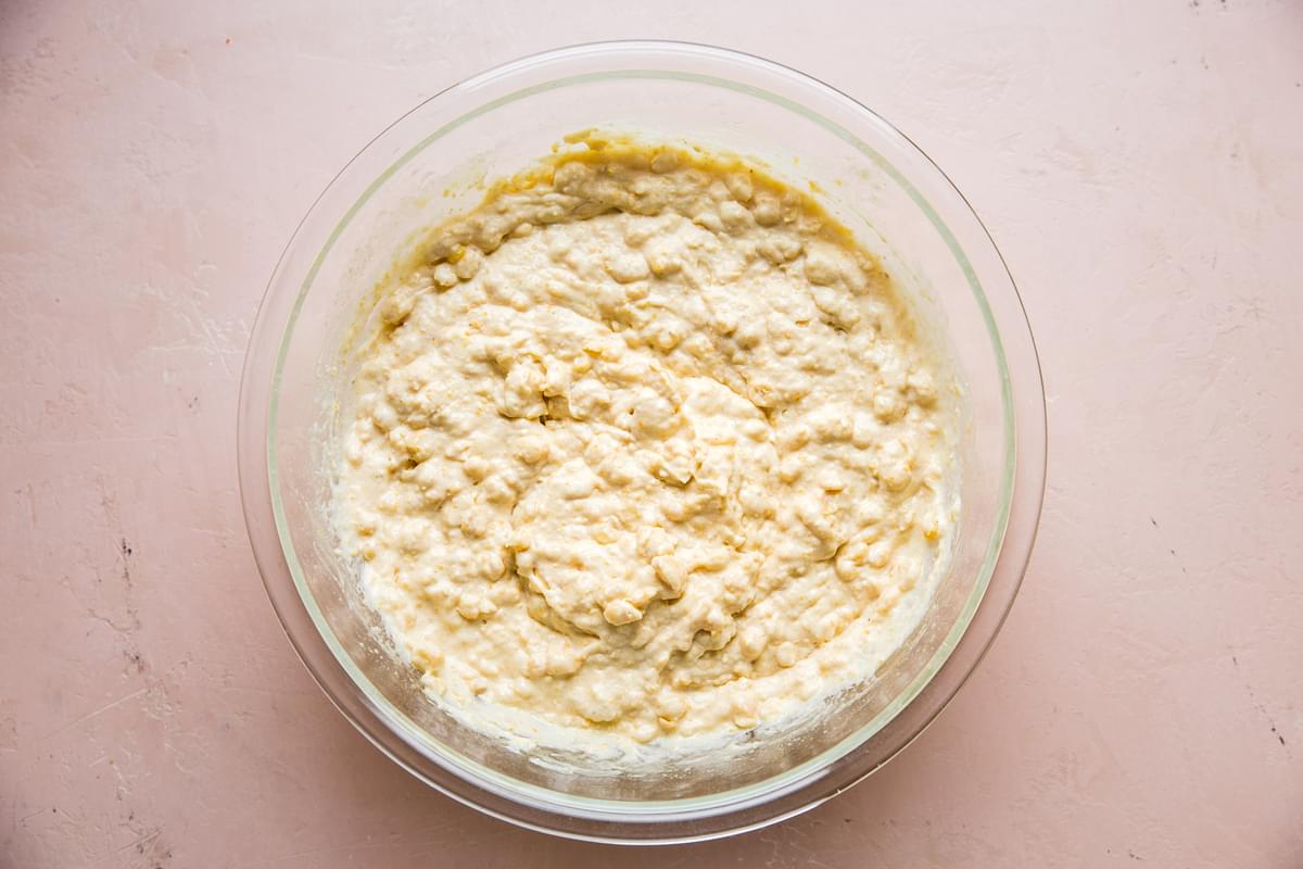spoon bread batter in a glass bowl made with flour, cornmeal, sugar, baking powder, salt, butter, eggs, corn & sour cream