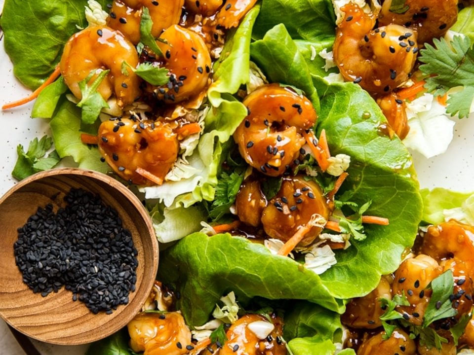 honey garlic shrimp lettuce wraps with and Asian cabbage slaw in butter lettuce on a plate with sesame seeds