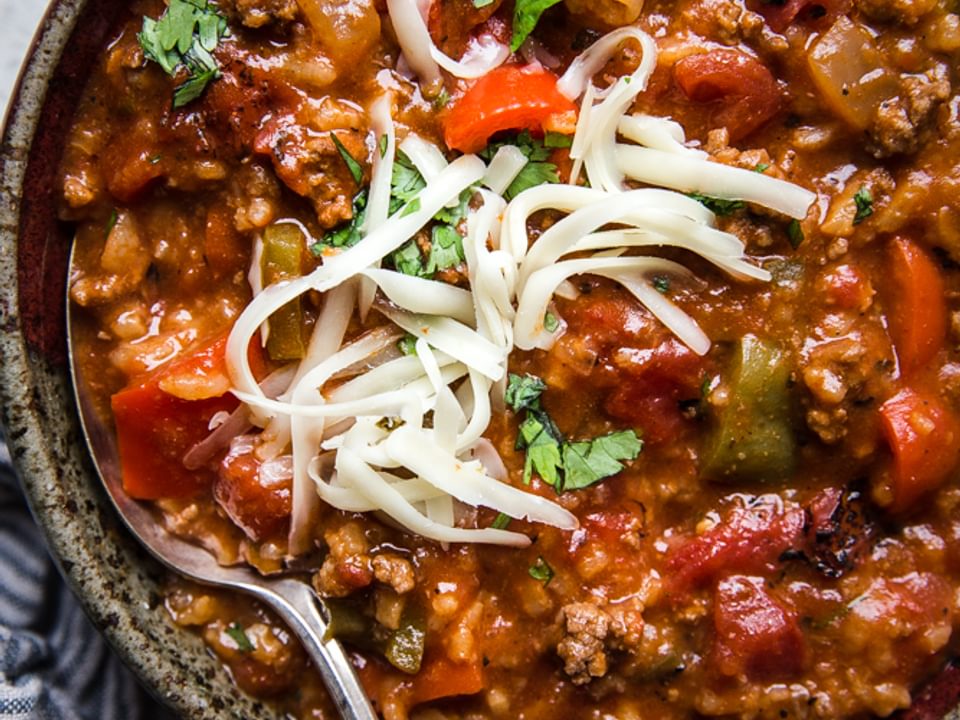 Stuffed pepper soup with ground beef, cilantro, shredded cheese in a bowl