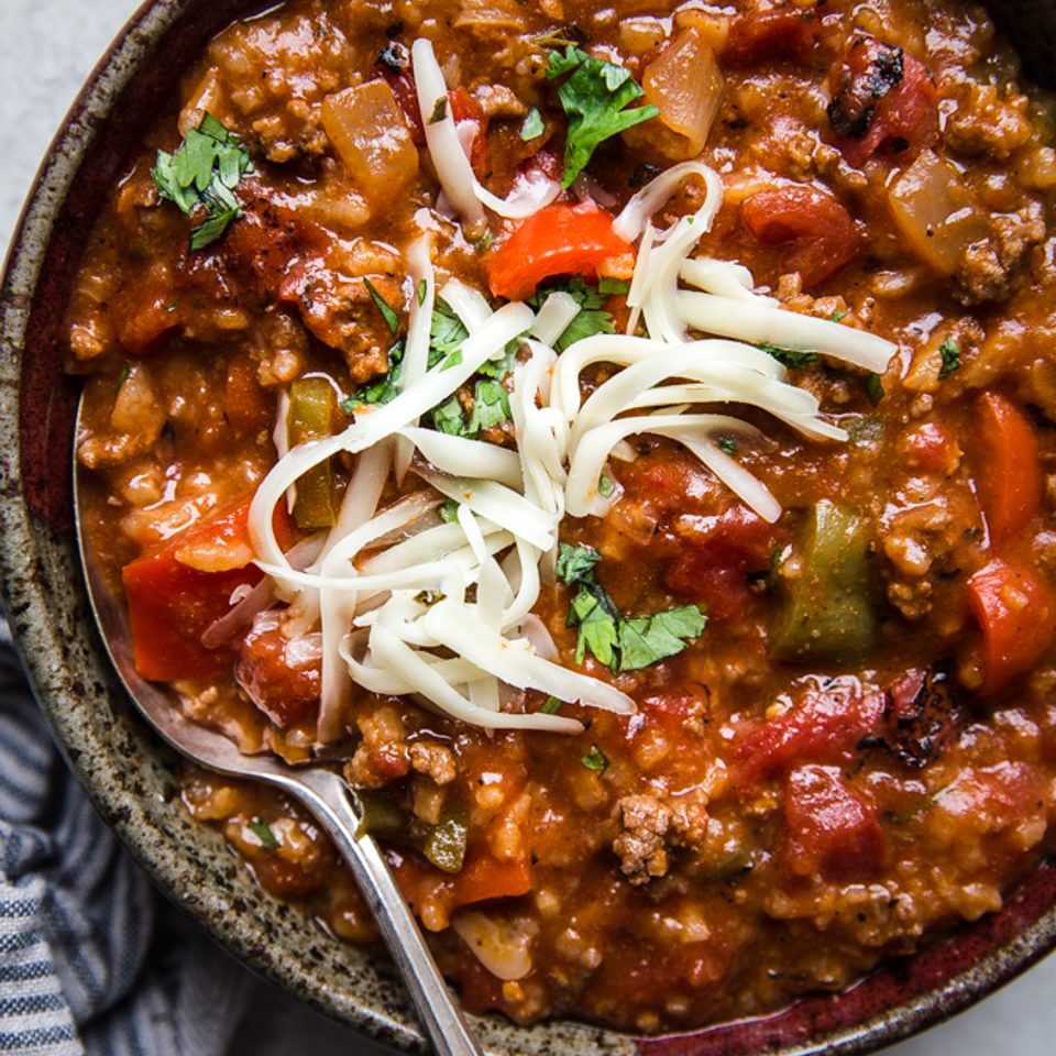 Stuffed pepper soup with ground beef, cilantro, shredded cheese in a bowl