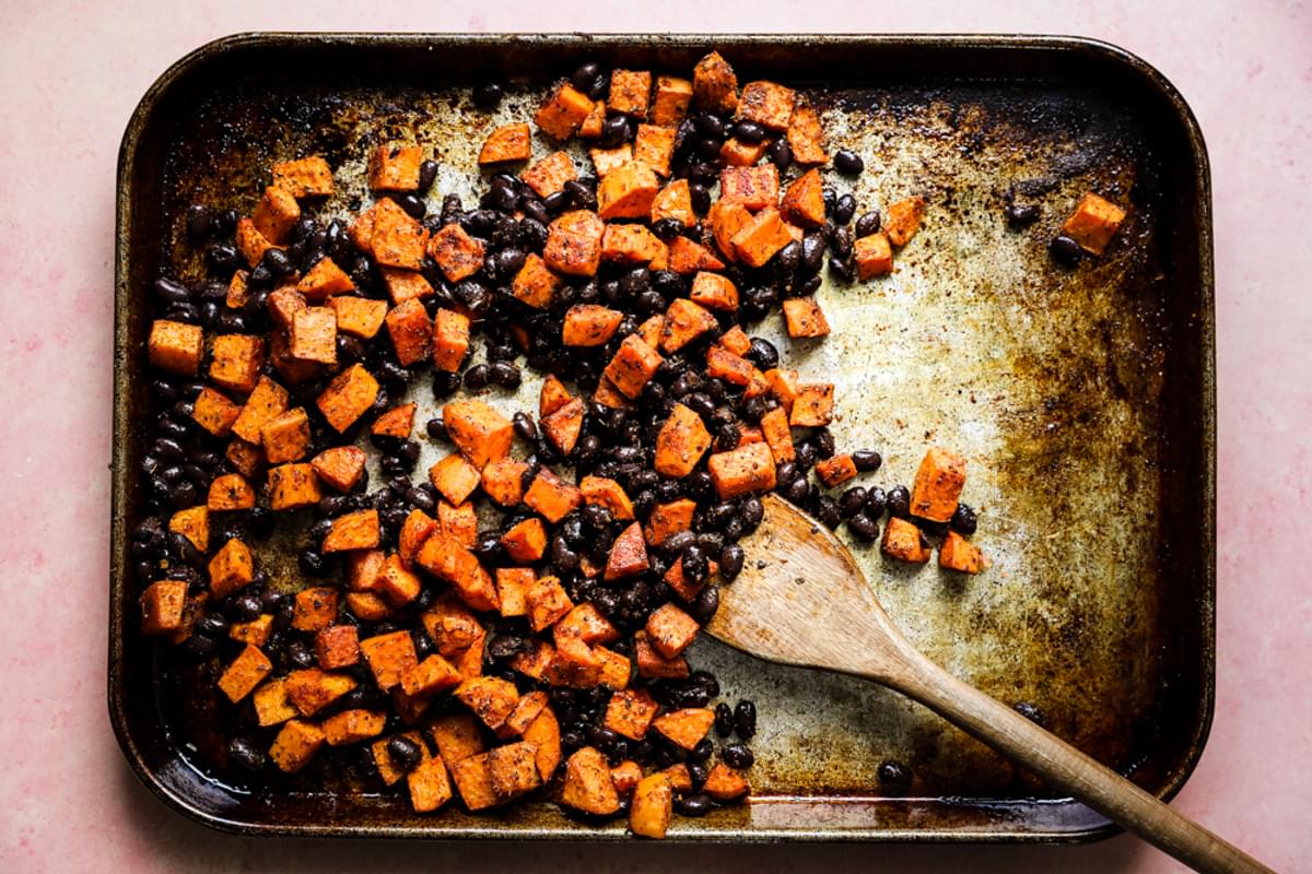 roasted sweet potato tacos with taco seasoning on a baking sheet mixed with black beans