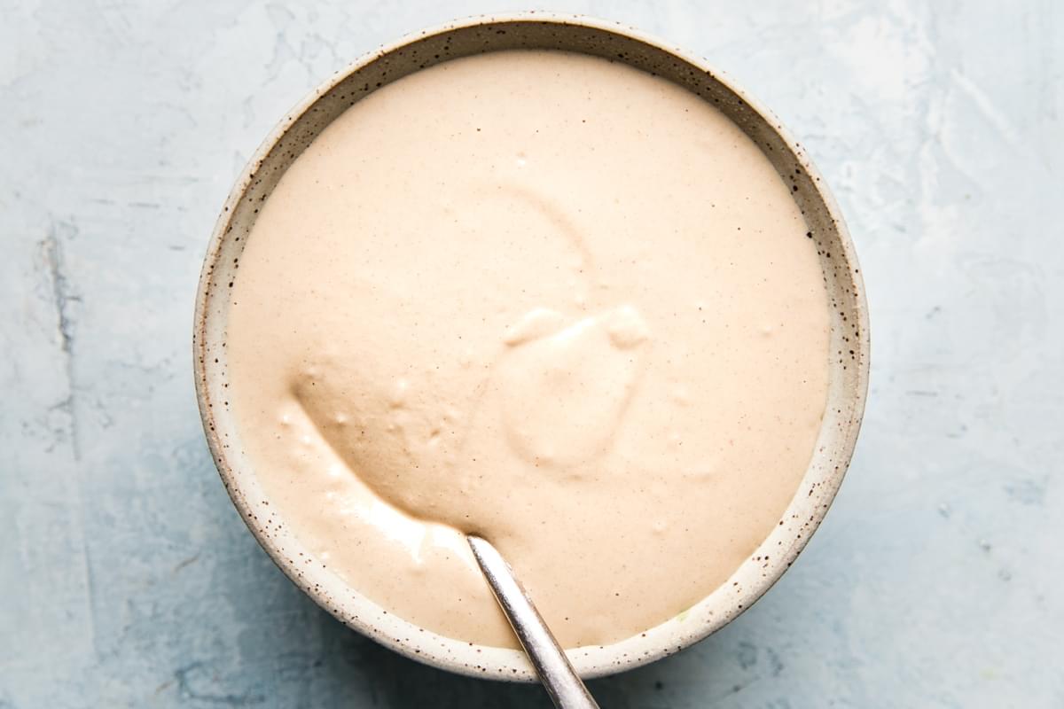 tahini sauce in a ceramic bowl with a spoon