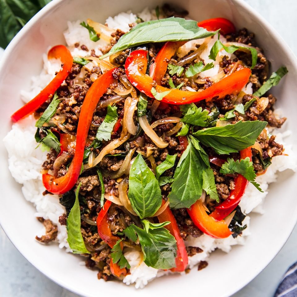 thai basil beef over white rice in a large white bowl
