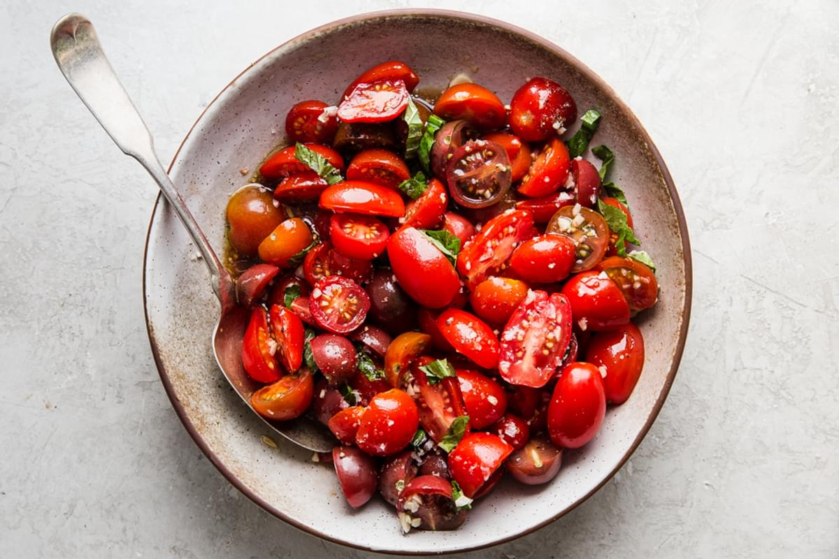 cherry tomatoes, balsamic, salt and garlic, lemon, basil, pepper and olive oil mixed together in a bowl