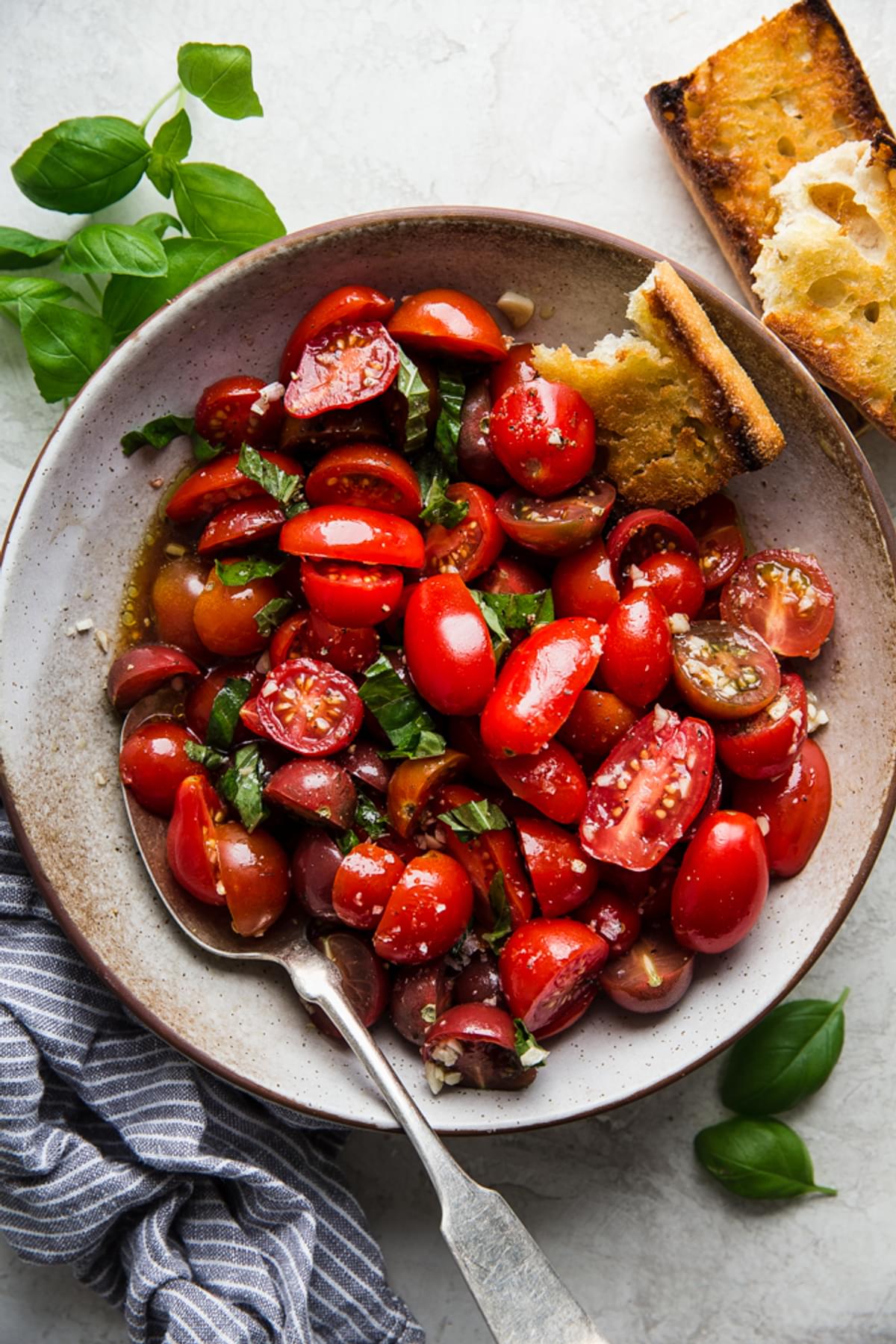 tomato salad with cherry tomatoes, balsamic, salt and garlic, lemon, basil, pepper and olive oil in a bowl with bread