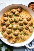 Turkey meatballs in a creamy red curry sauce topped with red pepper flakes and fresh cilantro.