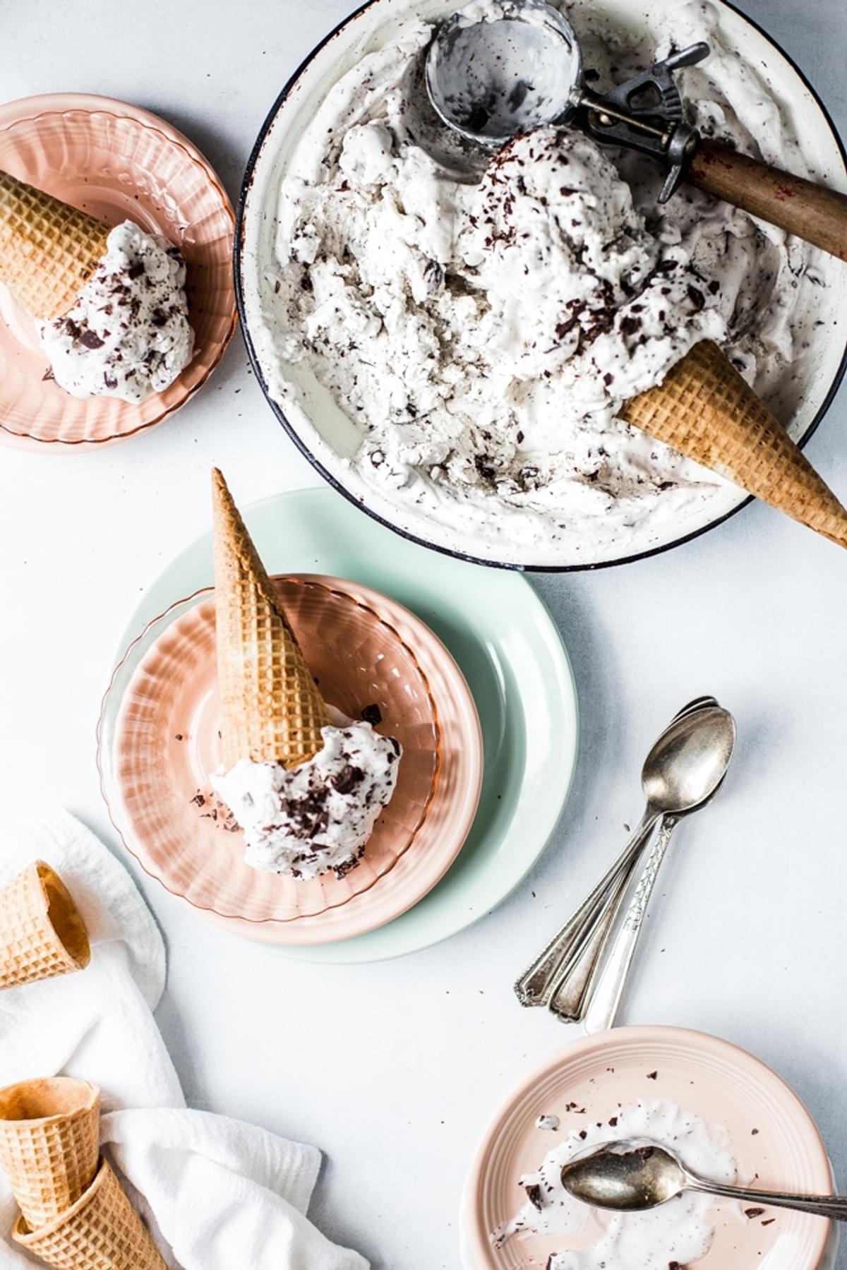 Vegan Mint Chip Ice Cream in a dish with cones and spoons and plates