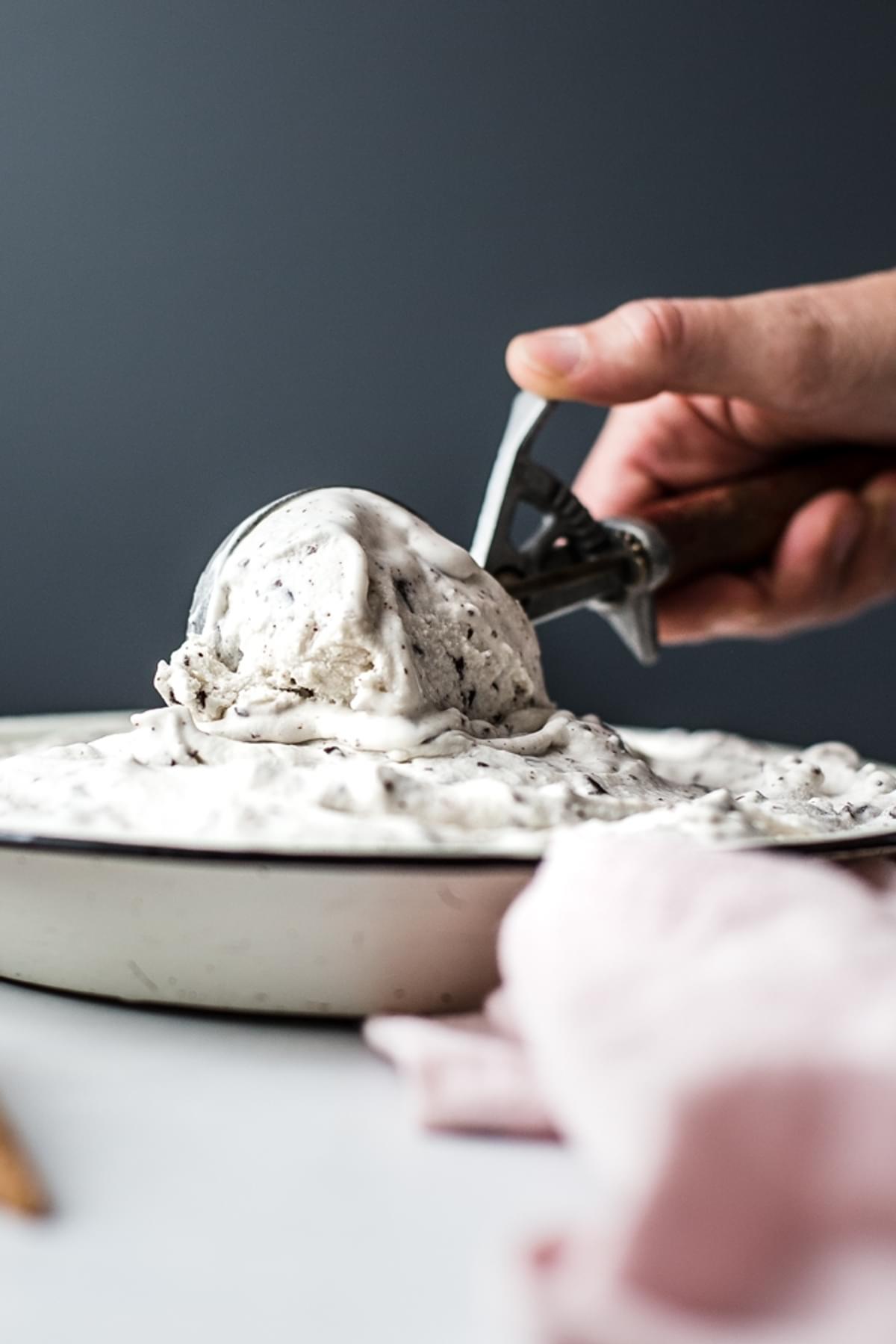 hand scooping Vegan Mint Chip Ice Cream out of a pie tin