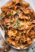 Walnut Vegan Bolognese with lentils with pasta on a plater with a serving spoon