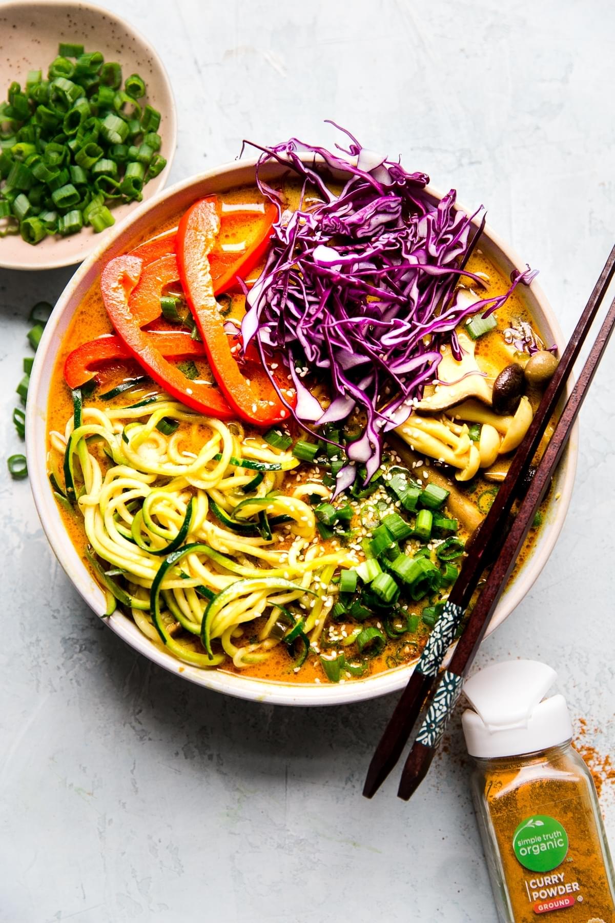 Coconut curry zoodle ramen with zucchini noodles, mushrooms  in a bowl with chop sticks. Vegan curry vegetarian curry.