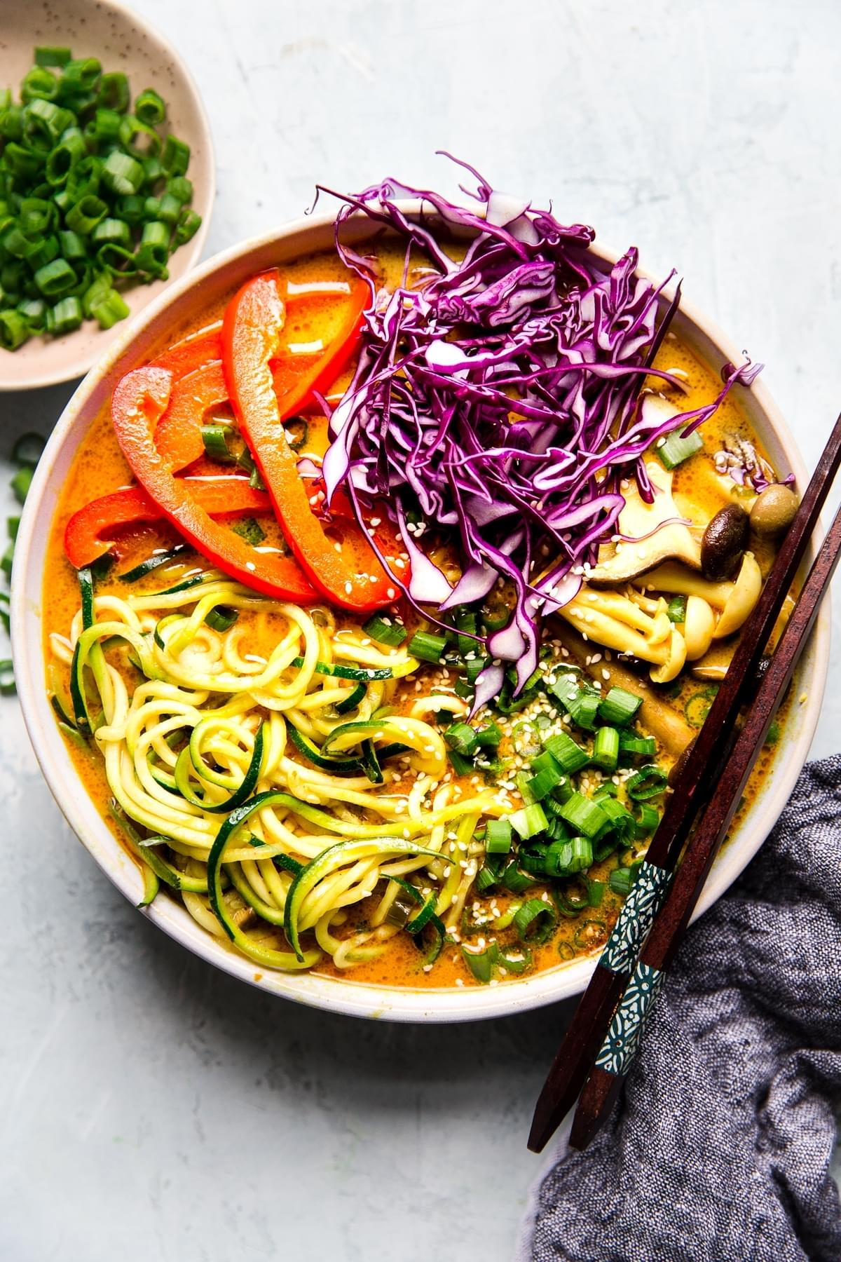 Coconut curry zoodle ramen with zucchini noodles, mushrooms  in a bowl with chop sticks. Vegan curry vegetarian curry.