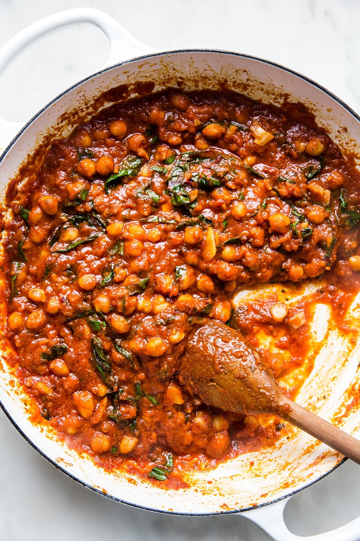 braised chickpeas in tomato sauce with a large wooden spoon