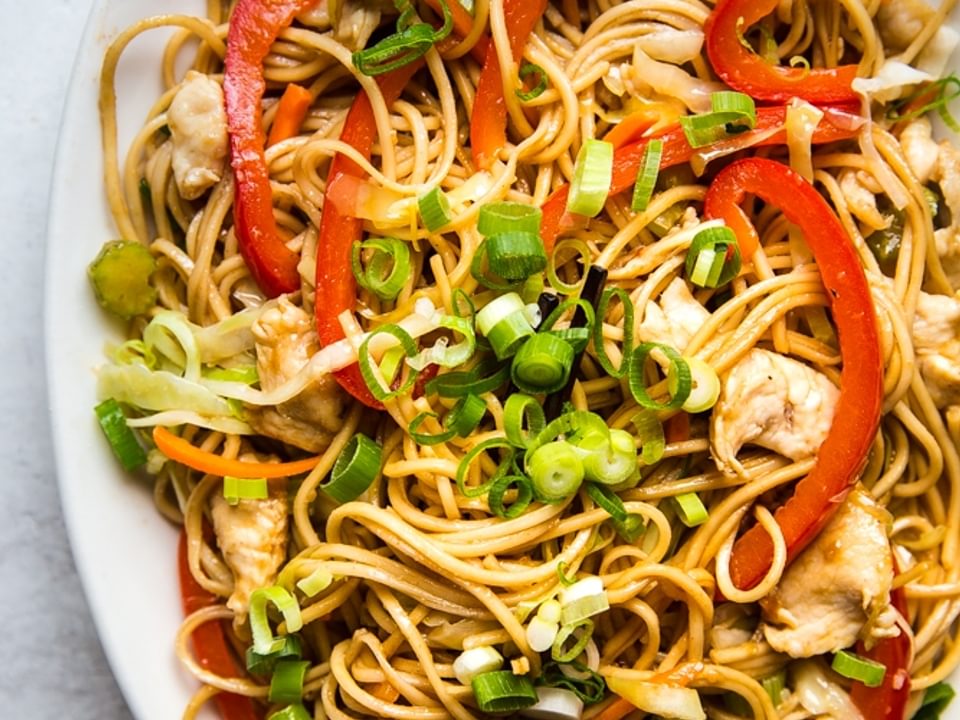 homemade chicken chow mein with carrots, cabbage, celery and green onion on a plate