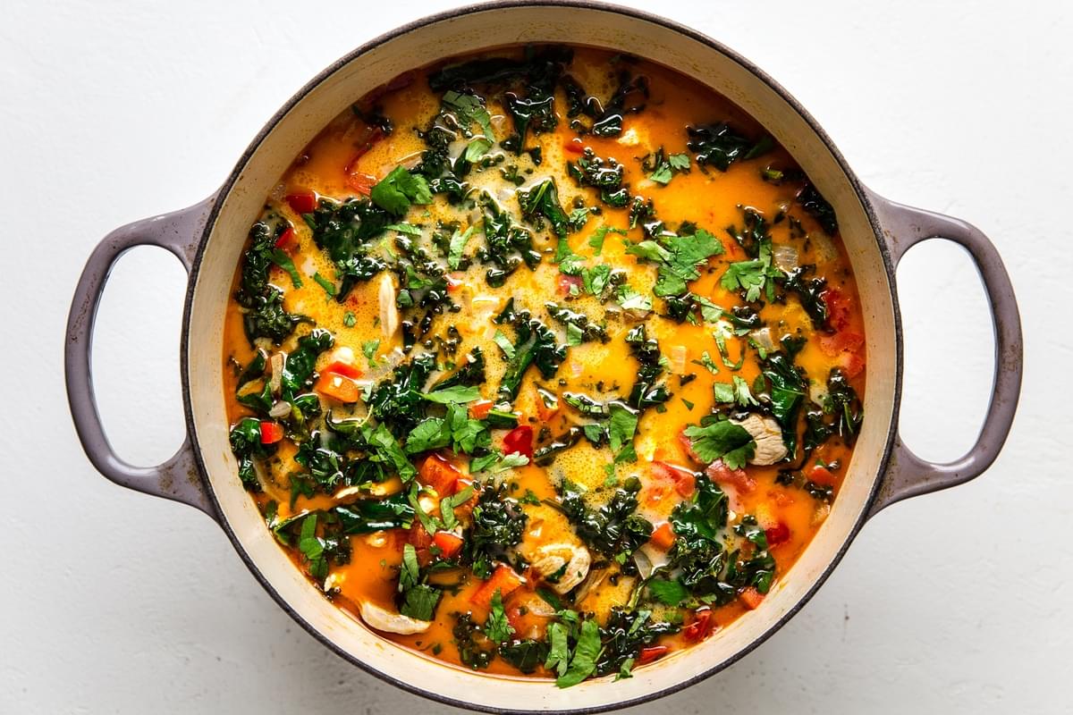 large pot of coconut curry soup with chicken, chickpeas, and kale