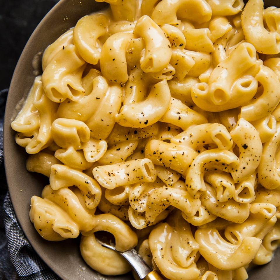 Instant pot mac and cheese in a bowl with pepper and a spoon