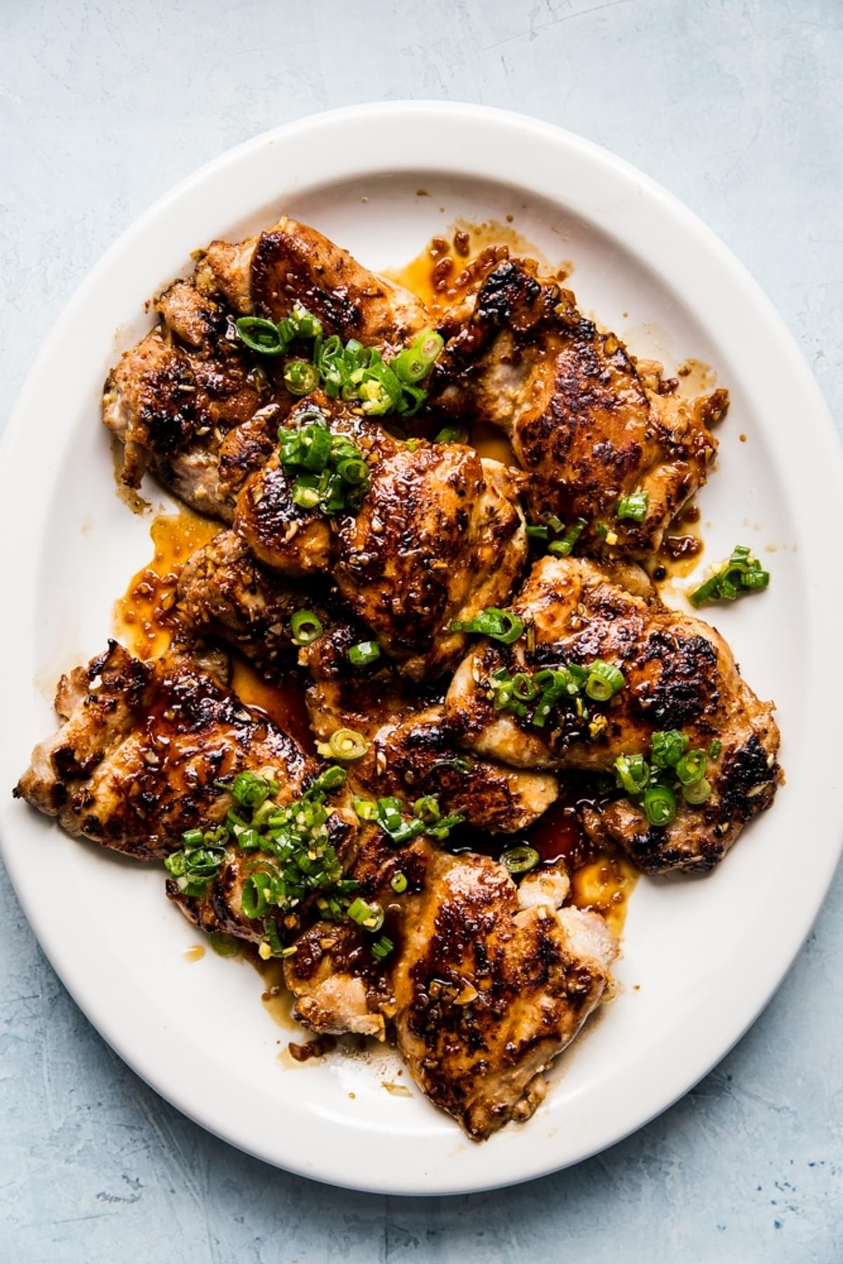lemongrass chicken thighs with scallion oil and a sriracha-brown sugar sauce on a plate