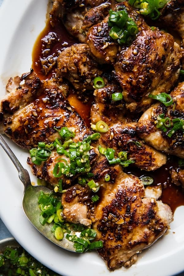 lemongrass chicken thighs with scallion oil and Asian bbq sauce on a plate with a serving spoon