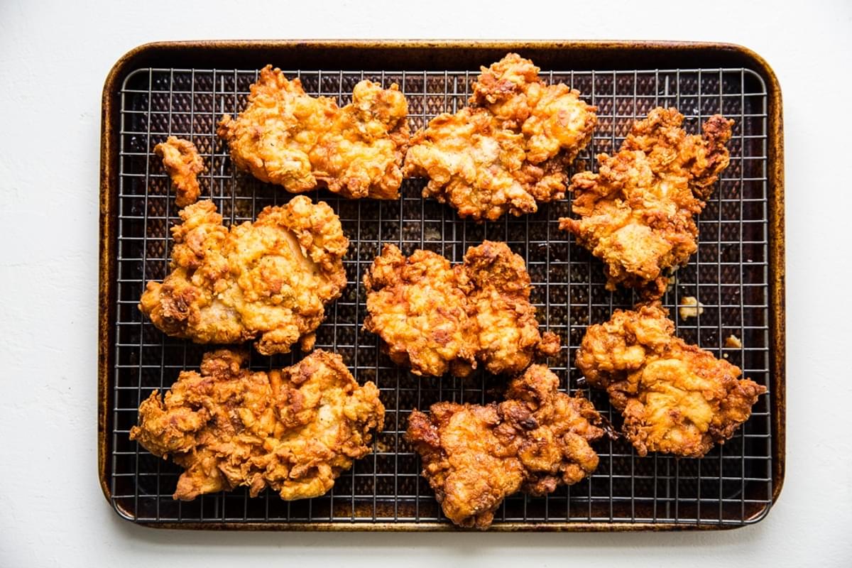 baking sheet lined with a cooling rack with eight pieces of perfectly fried chicken on top.