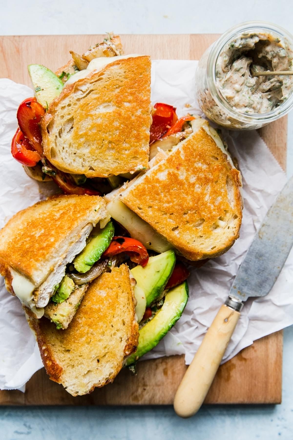 two grilled chicken sandwiches shown cut in half with avocado, grilled peppers and grilled chicken showing.