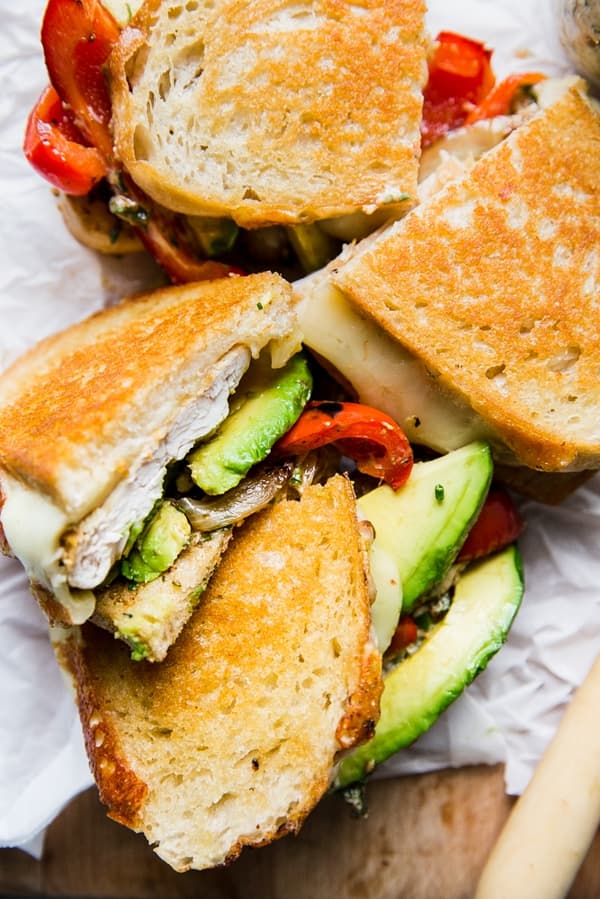 sante fe grilled chicken sandwich shown cut in half with avocados and grilled red peppers.
