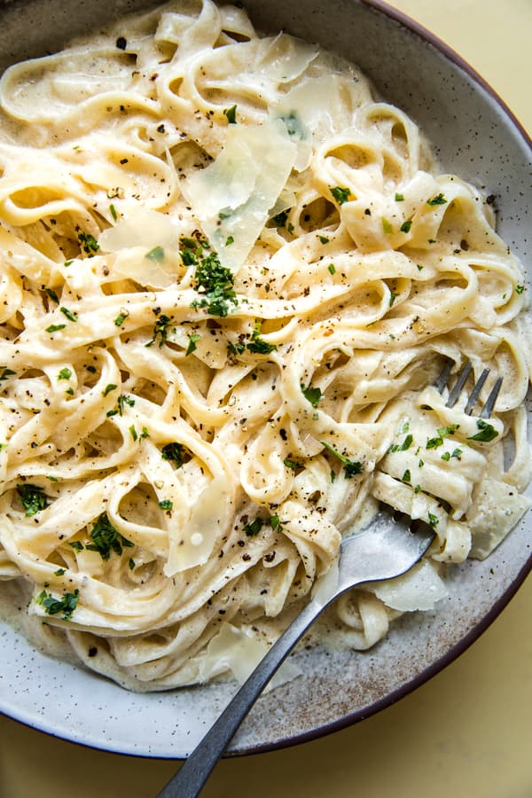a bowl of fettuccine with homemade Alfredo sauce topped with parmesan and parsley
