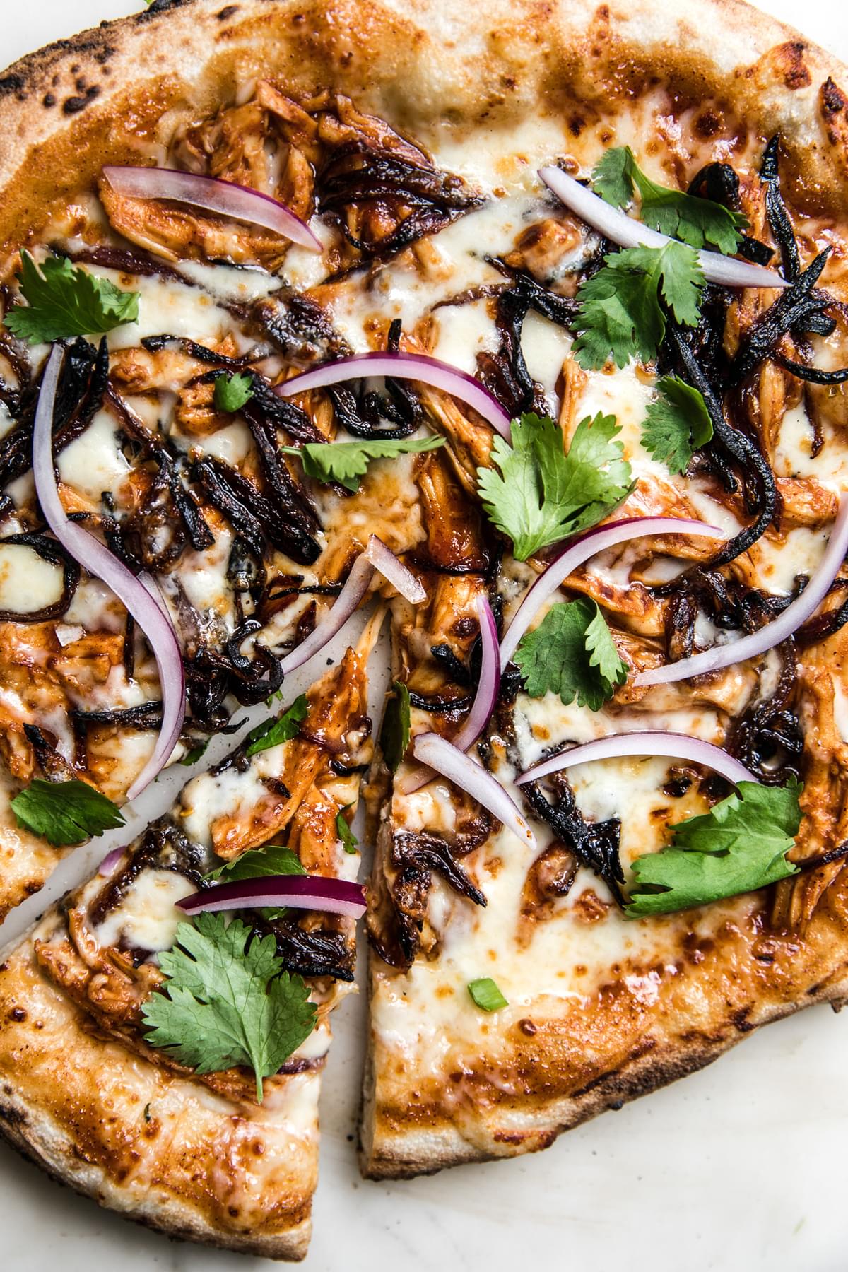 close up photo of bbq chicken pizza topped with fresh cilantro and red onions.