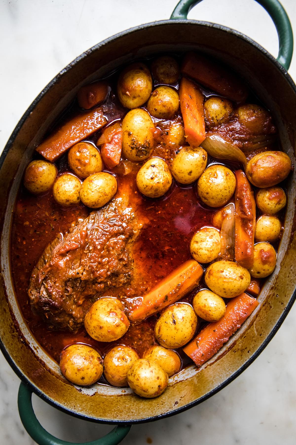 braised brisket with potatoes, carrots and onions in a dutch oven