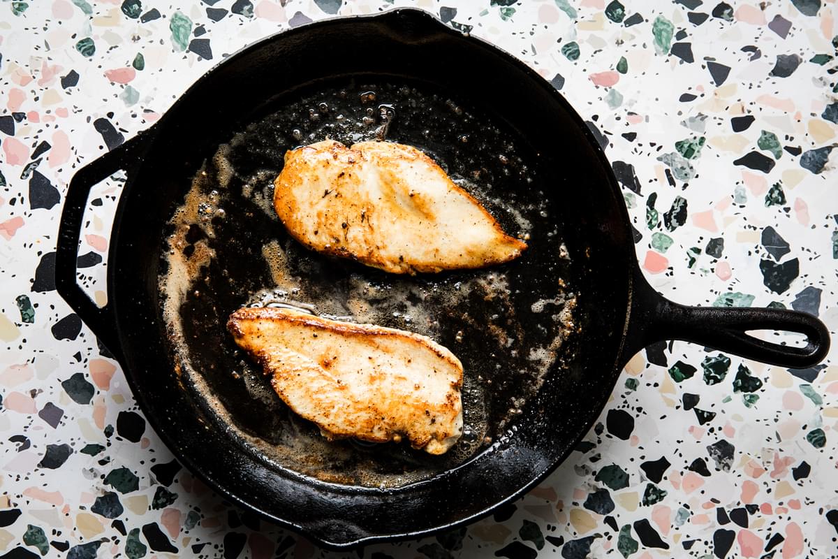 chicken paillards saute in butter and olive oil in a cast iron pan