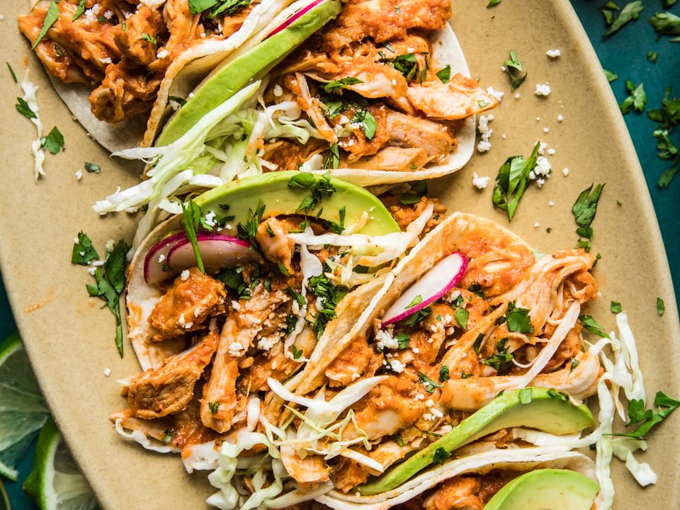 chicken tinga tacos in a platter with avocado and radishes