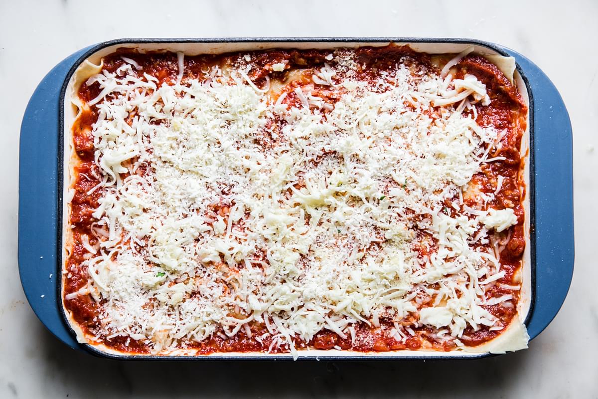 marinara meat sauce, topped with lasagna noodles topped with more sauce ricotta and mozzarella and parmesan in a lasagna pan