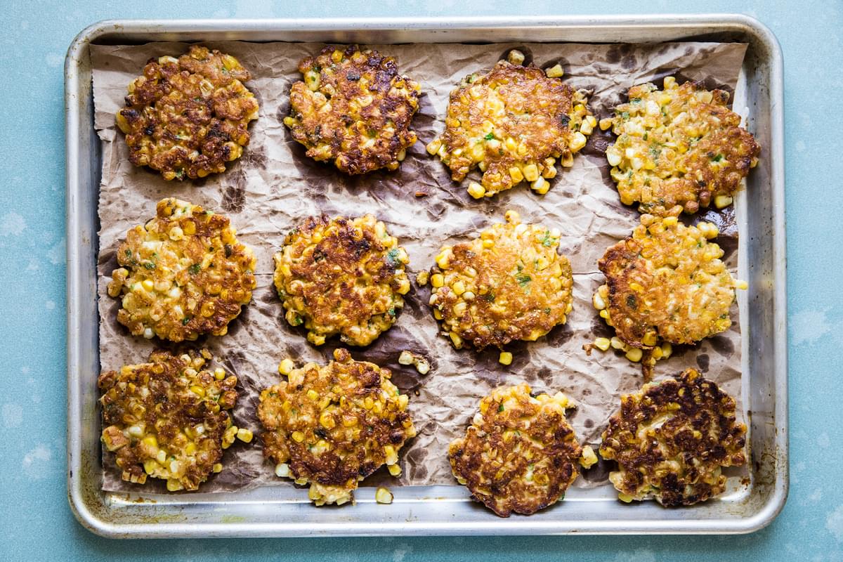 corn fritters on parchment paper on a baking sheet