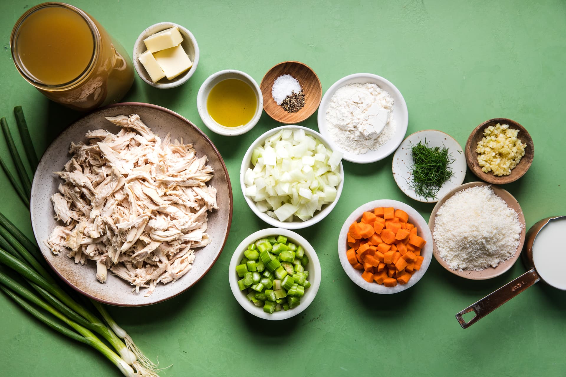 Shredded chicken, stock, green onions, rice, garlic, carrots and celery for creamy chicken soup in bowls on the counter