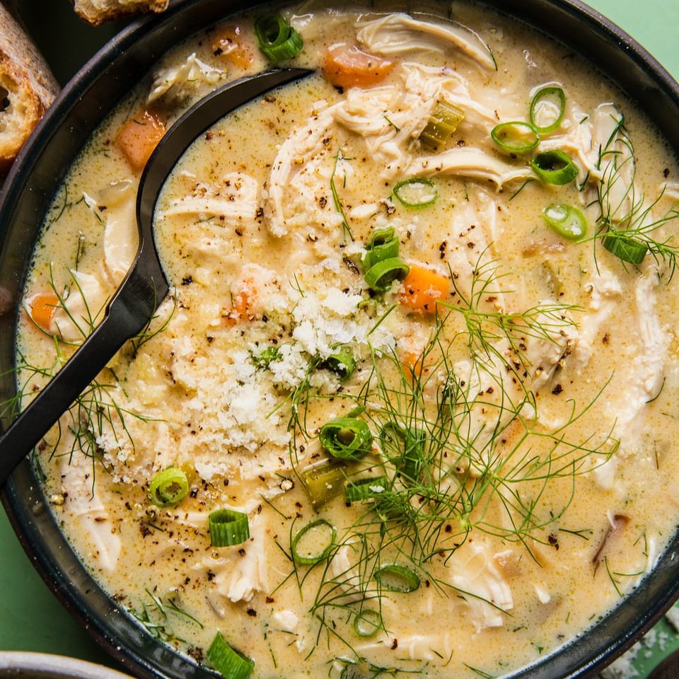 homemade creamy chicken soup in a bowl with a spoon served with crusty bread