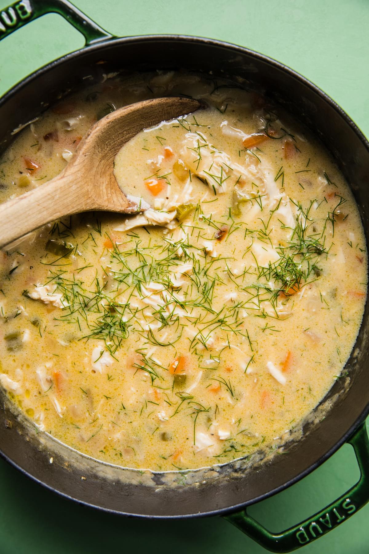 homemade creamy chicken soup in a pot with a wooden spoon